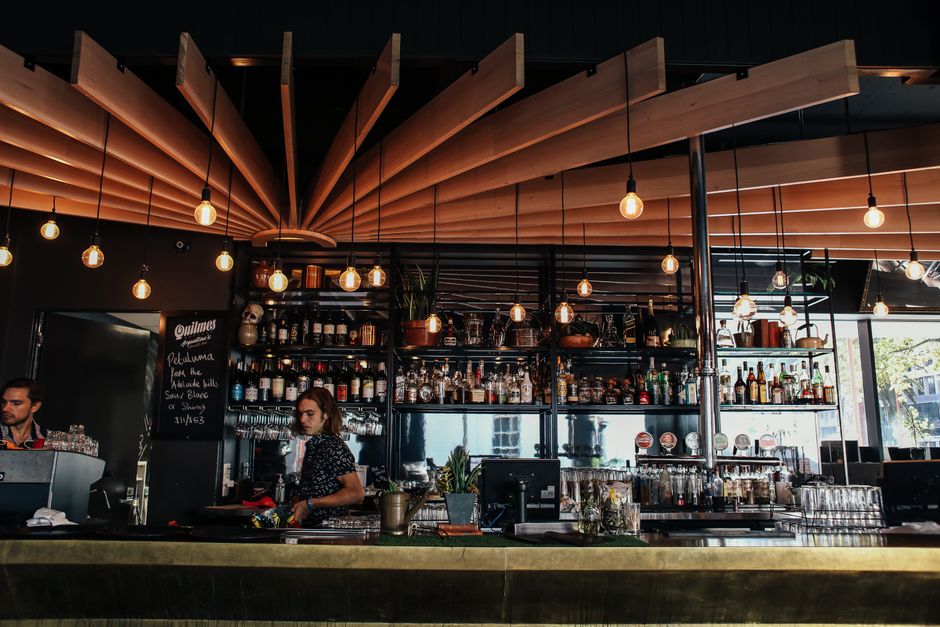 A bar counter with staff preparing drinks under warm lighting